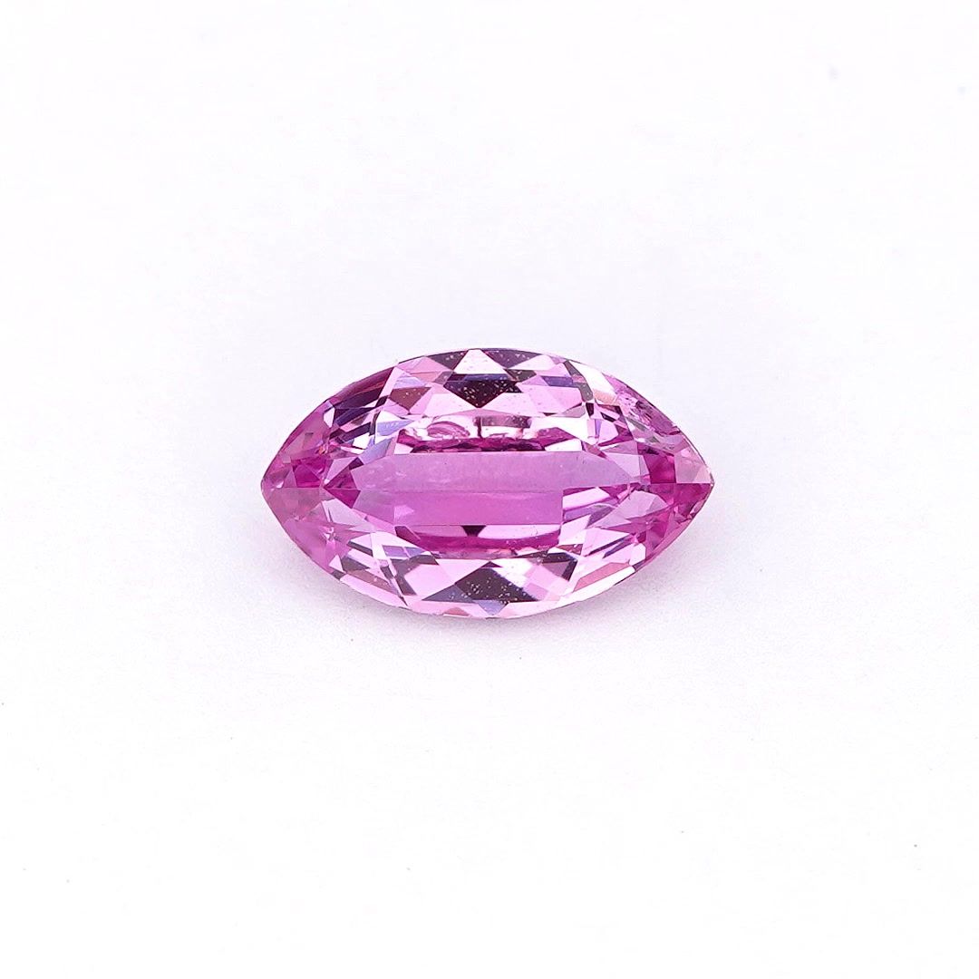 A faceted marquise-cut pink sapphire centered on a plain white background.