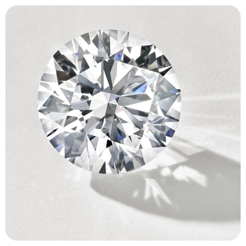 A round brilliant cut diamond shown from above on a light gray background with a soft shadow.