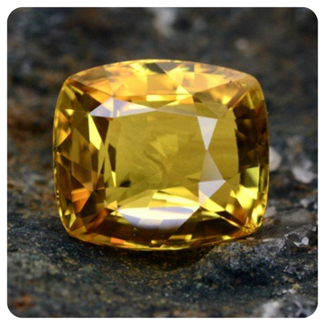Yellow sapphire gemstone on a textured dark surface