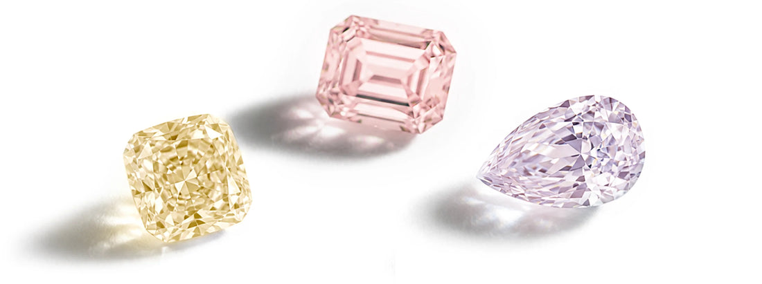 Three loose gemstones on a white background: a yellow cushion-cut diamond, a pink emerald-cut diamond, and a light purple pear-cut diamond.