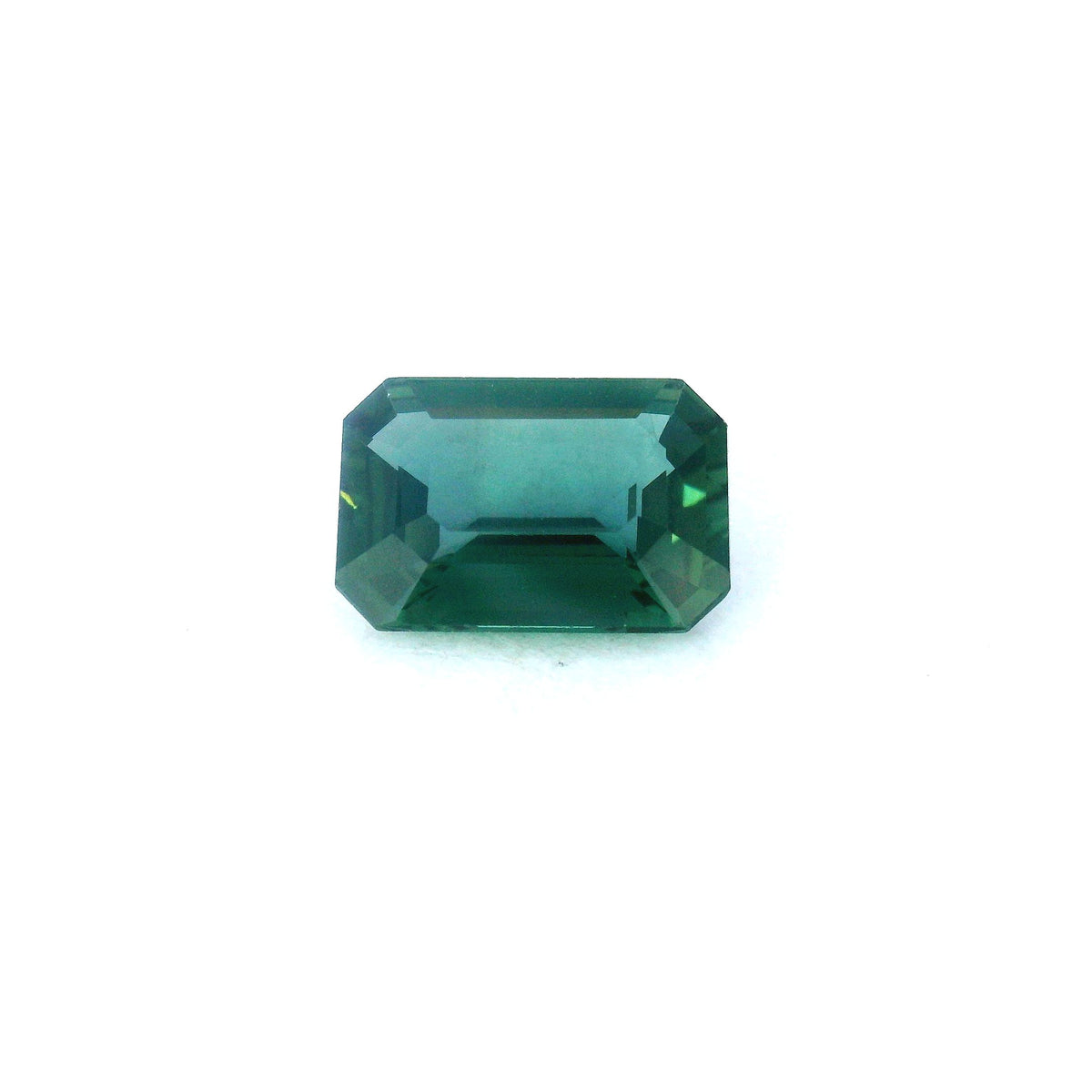 A rectangular emerald-cut green sapphire with faceted edges, centered on a plain white background.