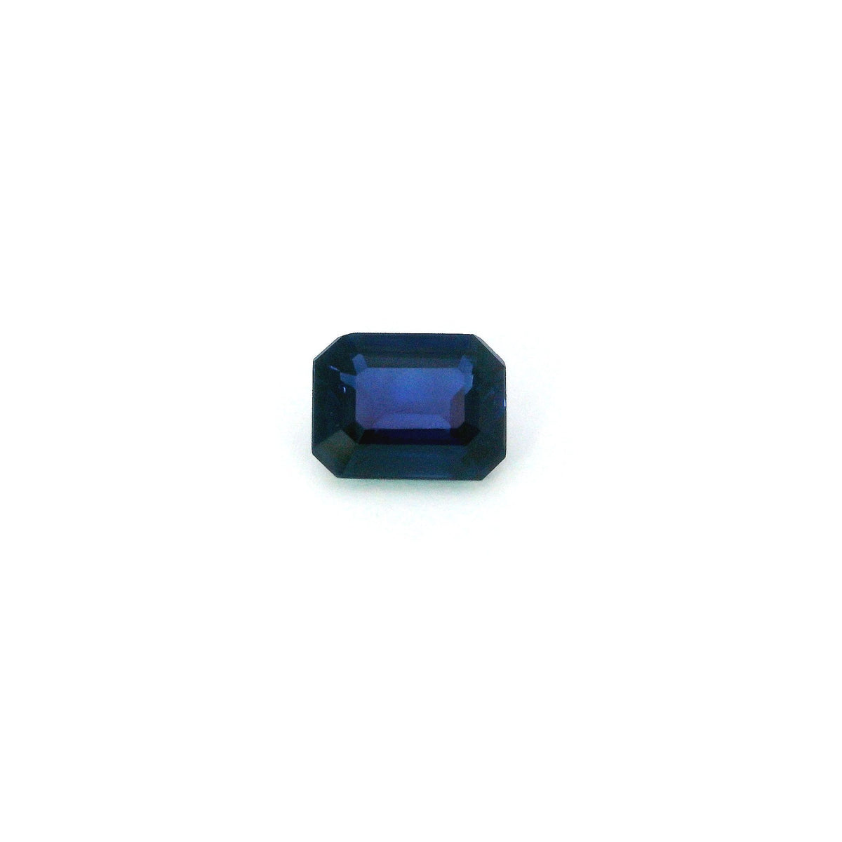 A single rectangular emerald-cut blue sapphire with a faceted surface, centered on a plain white background.