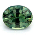 An oval-cut teal sapphire with a faceted, geometric pattern, shown on a plain white background.