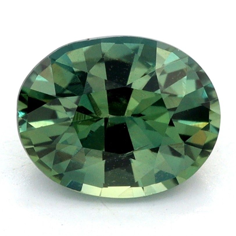 An oval-cut teal sapphire with a faceted, geometric pattern, shown on a plain white background.